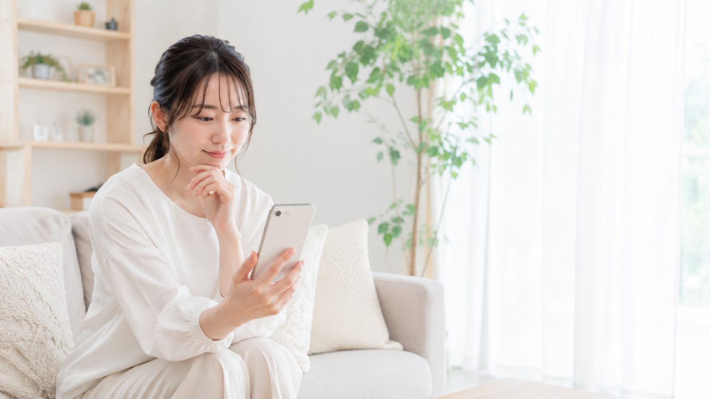 自宅のソファでスマートフォンから歯の悩みを相談する女性